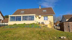a yellow house on top of a grassy hill at Chez Betty in Semur-en-Auxois