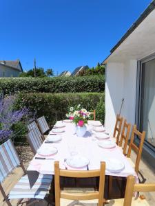 a long table with plates and flowers on a patio at Maison les dunes proche plage in Quiberon