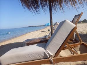 a chair and table on a beach with the ocean at Bamboo garden in Nea Iraklia