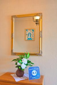 un espejo sobre una mesa con un reloj y flores en Apartment and Rooms Toka, en Zadar