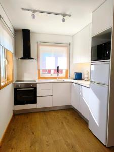 a kitchen with white cabinets and a sink and a window at Herama Sea Guesthouse in Vila Nova de Gaia +11 photos