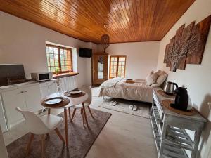 a bedroom with a bed and a table and a kitchen at Studio proche de la cité médiévale Crémieu in Dizimieu