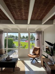 a living room with a chair and a sliding glass door at NIEUW Bootique Frysk huske Langweerderwielen in Boornzwaag