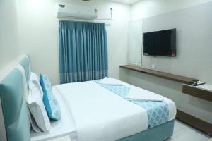 a hotel room with a bed and a flat screen tv at Hotel Greenland in Khammam