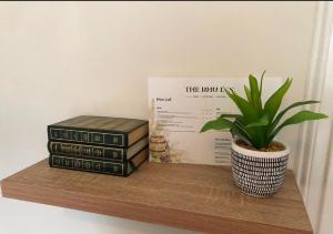 Una pila de libros y una planta en maceta en un estante en The Rhu Inn, en Rhu