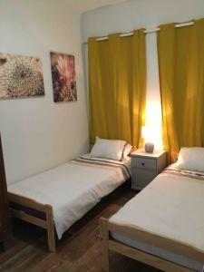 - 2 lits dans une chambre dotée de rideaux jaunes dans l'établissement La Bergerie, à Pessac-sur-Dordogne