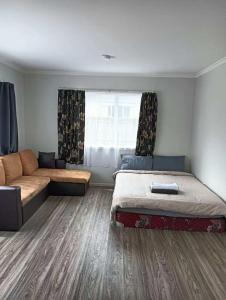 a bedroom with two beds and a couch and a window at 5 Beds including 3 Double Beds and 1 Double or 2 Single Sofa Beds at 22A Pererika Street in Rotorua +11 photos