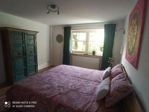 Un dormitorio con una cama morada y una ventana. en Galerie Storm, en Haby