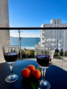 two glasses of wine on a table with a view of the ocean at Calypso Sea View Apartament Saranda in Sarandë