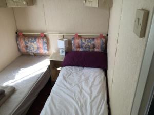 a small bedroom with a bed in a small room at Caravan in Moelfre village in Moelfre