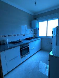 a kitchen with white appliances and a large window at Noor Home in Chefchaouen