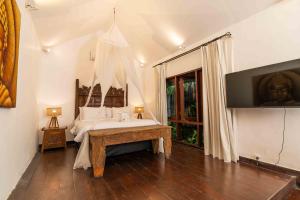 スミニャックにあるThe Gardens Seminyakの白いベッドとテレビのある寝室