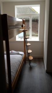 Sint MaartensbrugにあるApartment Vredehofのベッドルーム1室(二段ベッド1組付)、窓際の梯子が備わります。