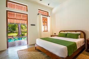 a bedroom with a bed and a window and a pool at Origin Balapitiya- Family Villa 200m From Beach in Balapitiya