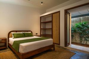 a bedroom with a bed with green pillows and a window at Origin Balapitiya- Family Villa 200m From Beach in Balapitiya