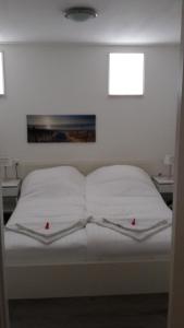 Una cama con sábanas blancas y dos estrellas rojas. en Apartment Vredehof, en Sint Maartensbrug
