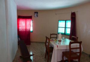 a dining room with a table with chairs and red curtains at Chez Niominka Bi à Niodior in Poundiougne +11 photos