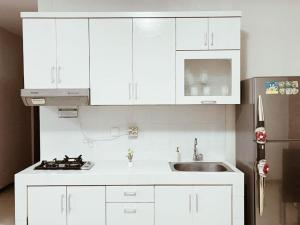 a kitchen with white cabinets and a sink and a refrigerator at Premium Getaway in City Central in Jakarta