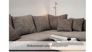 a couch with pillows and a table with a book at Strandvilla Haffkrug Apartment Strandläufer in Scharbeutz