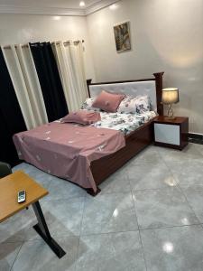 a bedroom with a bed with pink sheets and pillows at Viamo Lodge Apartments in Kumasi