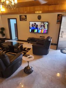 a living room with couches and a flat screen tv at Viamo Lodge Apartments in Kumasi