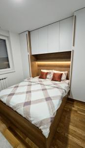 - une chambre avec un grand lit et des placards blancs dans l'établissement Stan na dan-Apartman Mia, à Lukavica