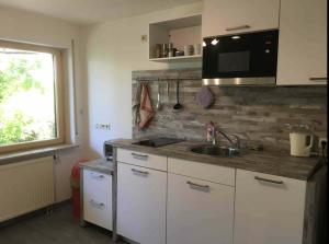 a kitchen with white cabinets and a sink and a window at Schurwaldwohnung Adelberg in Adelberg