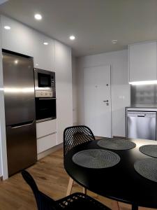 eine Küche mit Tisch und Stühlen und einem Kühlschrank in der Unterkunft Claudia Luxury Apartment near the beach with a pool, gym, and secure gated parking in Arenales del Sol