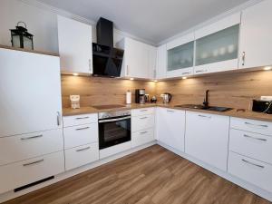 a white kitchen with wooden floors and white cabinets at Ferienwohnung Angela in Walchum