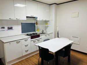 a kitchen with white cabinets and a table with chairs at Travel Apartment in Seoul +40 photos