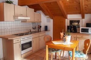 a kitchen with a wooden table and a table and a stove at Gänseblümchen -805- in Mittenwald