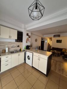 a kitchen with white cabinets and a living room at Angel apartament in Sibiu