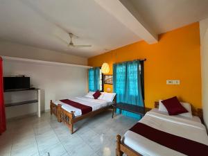 a hotel room with two beds and a tv at Mountain View Villas in Madikeri