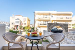 a table with two chairs and a bowl of fruit on a balcony at Brand New House Sitia in Sitia