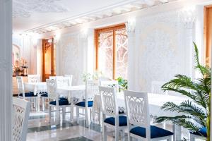 a white dining room with a white table and chairs at Hotel Caravan Serail in Samarkand