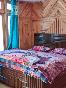 a large bed in a room with wooden walls at Shivaay guest house in Tosh