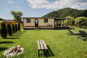 a log cabin in a field with a bench in the grass at La Casuta din Ciocanesti Exclusive in Ciocăneşti