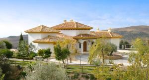 a large white house with a fence in front of it at Villa Los Chaparros, luxury, tranquillity and culture in the heart of Andalusia in Antequera