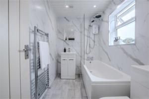 une salle de bain blanche avec une baignoire et un lavabo dans l'établissement Jasmine Cottage, à Skipsea 18 autres photos