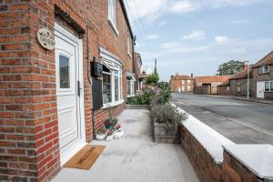 un bâtiment en briques avec une porte blanche dans une rue dans l'établissement Jasmine Cottage, à Skipsea