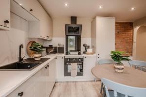 une cuisine avec des armoires blanches et une table en bois dans l'établissement Jasmine Cottage, à Skipsea