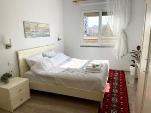 a bedroom with a white bed with a red rug at Capital Apartment Tirana in Tirana