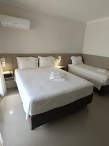 two beds in a room with white walls at Pousada Azimute in Torres