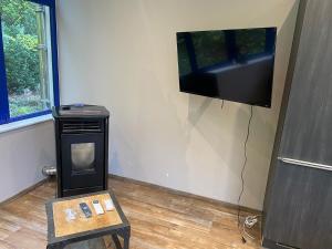 a living room with a tv on the wall and a table at duplex romantique in Clavier
