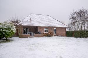 a brick house with snow on the ground at Aurora#1 mit großem Garten, Sauna und Kamin in Wiesmoor