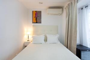 a bedroom with a bed with white sheets and a window at Braganca Oporto in Porto