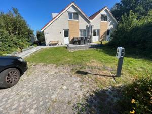 a car parked in front of a house with a mailbox at familienfreundliches Ferienhaus mit Ruderboot, Sauna und Kamin sowie E-Ladestation in Makkum