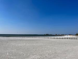 a sandy beach with a fence and the ocean at familienfreundliches Ferienhaus mit Ruderboot, Sauna und Kamin sowie E-Ladestation in Makkum