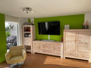 a living room with a television on a green wall at familienfreundliches Ferienhaus mit Ruderboot, Sauna und Kamin sowie E-Ladestation in Makkum +16 photos