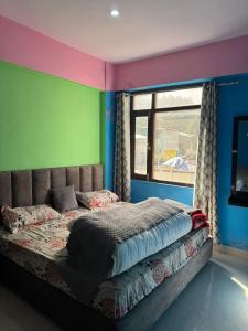 a bedroom with a bed with colorful walls and a window at Celebrate Vacation New Shanti Palace in Badrīnāth